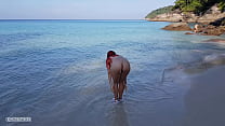 Chica pelirroja desnuda se baña en una playa pública