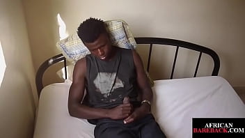 Соло африканского спортсмена поглаживает его необрезанный член на кровати